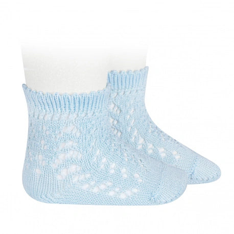 Light blue baby socks with white polka dots on a white background