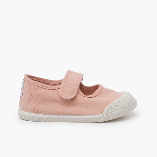 Pink children's shoe with a white sole on a light beige background