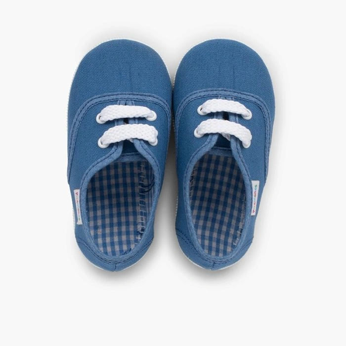 Pair of blue children's shoes with white laces on a white background