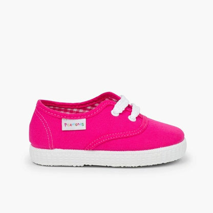 Pink children's shoe with white sole on a light gray background