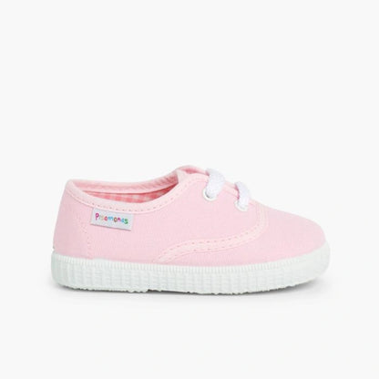 Pink children's shoe with white sole on a white background