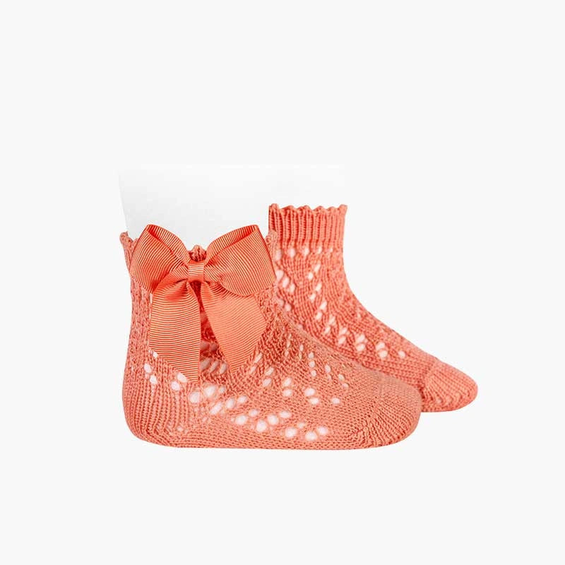 Peach baby socks with a bow on a white background