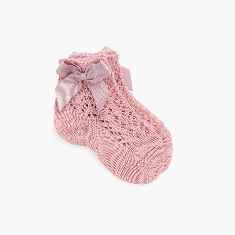 Pink knitted baby sock with a bow on a white background