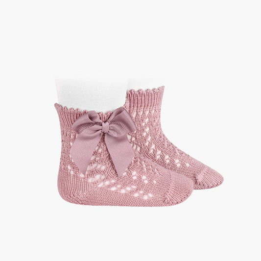 Pink knitted socks with a bow on a white background