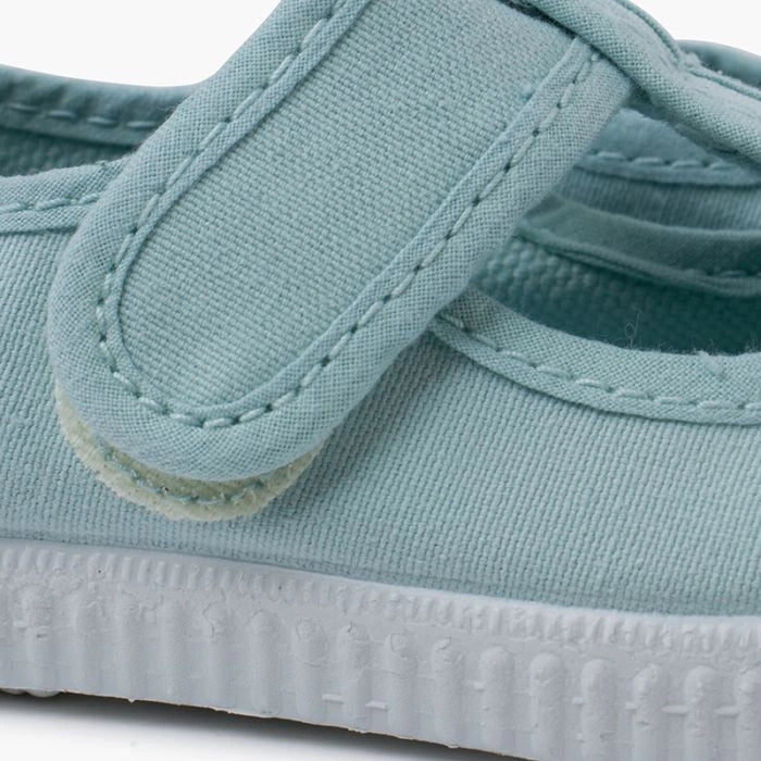 Light blue children's shoe with a white sole on a white background