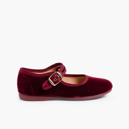 Red velvet shoe with a gold buckle on a white background
